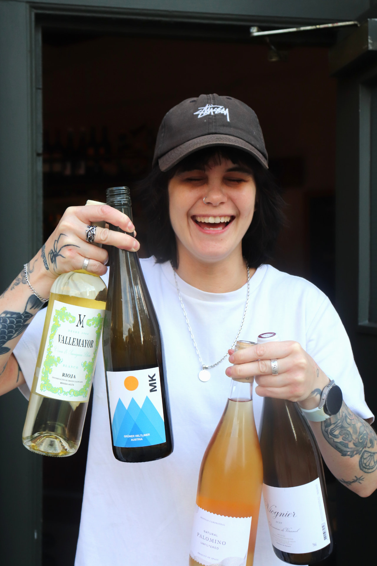 Smiling staff member holding four bottles of wine